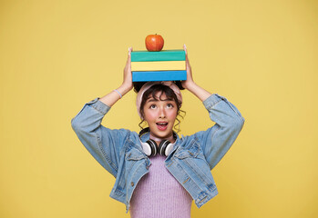 back to school. happy smiling young Asian college student with book and red apple on head ready to...