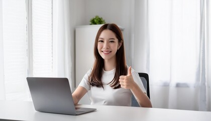 ノートパソコンを使っている若いアジア人の女性がいいねをしてる。（A young Asian woman using a laptop gives a thumbs up.）
