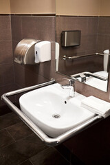 Interior of specially adapted bathroom toilet with friendly design for people with disability handicapped with disabilities or invalids in wheelchair with handrail handle toilet.