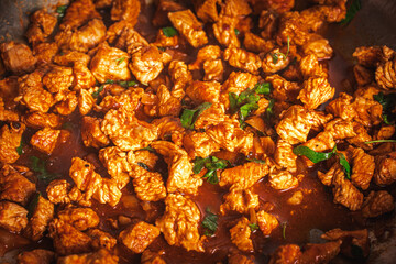 The turkey, cut into small pieces, is fried in a pan in tomato sauce with parsley.