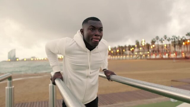 Side view of young strong man doing dips&nbsp;on parallel bars