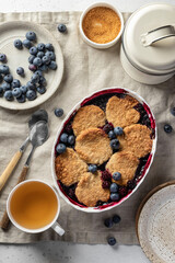 Homemade blueberry cobbler pie in baking dish on linen tablecloth table top view, flatly, sweet breakfast