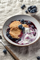 Homemade blueberry cobbler pie served with scoop of ice cream in ceramic plate on linen tablecloth table, sweet breakfast