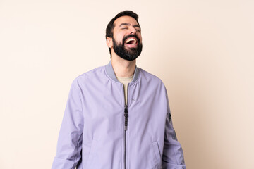 Caucasian man with beard wearing a jacket over isolated background laughing