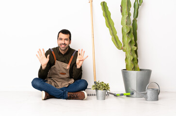 Gardener man sitting on the floor at indoors counting nine with fingers