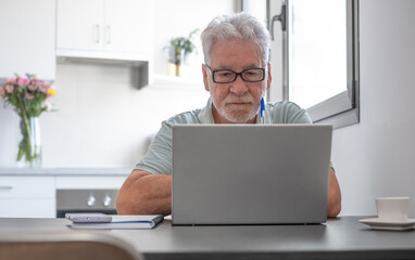 Video call concept.  Serious senior caucasian businessman working online on laptop  sitting at home desk, remote working