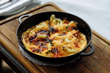 delicious dish with crispy potatoes, fresh vegetables, fragrant herbs, and creamy cheese served on a beautiful black plate in a cozy, charming café
