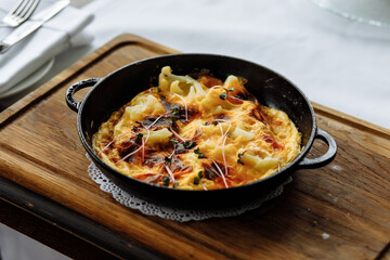 delicious dish with crispy potatoes, fresh vegetables, fragrant herbs, and creamy cheese served on a beautiful black plate in a cozy, charming café