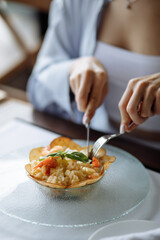 lovely girl is enjoying a delicious dish with juicy shrimp, grains, fresh vegetables, and fragrant herbs on a beautiful white plate in a cozy and charming café