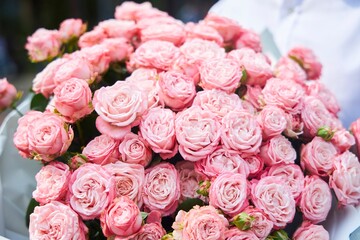 A bouquet of pink roses is being held by a person. The flowers are arranged in a way that they are all facing the same direction