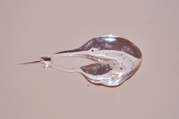 A drop of lubricant or cosmetic gel on a pink background.
