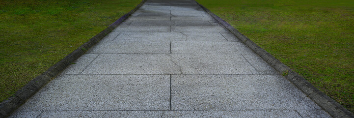 Fototapeta premium curb along the edge of the walkway is flush with the paving. Green Grass Grows Near Paving concrete Slabs Or Tail, Separated By Concrete Border. Road And Lawn Divided By Concrete border. crosswalk