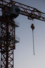 Naklejka premium chains, Hook from a tower crane for lifting cargo isolated on blue sky background. mobile construction crane lifts a load with a hook and chains. Close-up of a construction crane hook at work