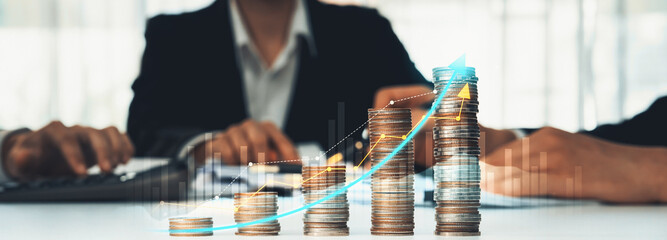 Coin stack with digital graphic indicator symbolizing business investment and economic growth. Businessman doing financial planning to achieve financial goal and contribute to profit. Shrewd