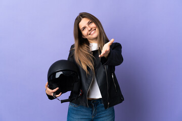 Young slovak woman holding a motorcycle helmet isolated on purple background shaking hands for closing a good deal