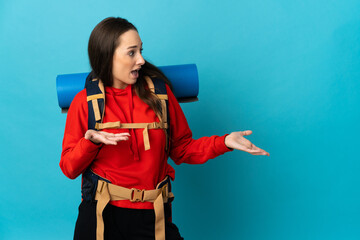 Mountaineer woman with a big backpack over isolated background with surprise expression while looking side