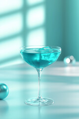 Refreshing turquoise cocktail is standing on a table, its color matching the background, with window light reflections