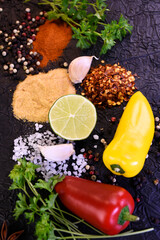 Seasoning for cooking. Pepper, salt, garlic, parsley on a black background. Ingredients to flavor food