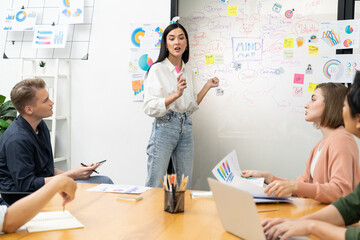 Young beautiful leader presents marketing strategy while expert investor and project manager lecturing to analyze business performance at start up business meeting. Multiethnic group. Immaculate.