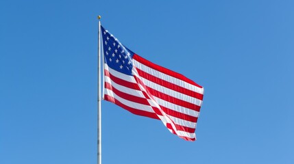 Fototapeta premium A patriotic shot of the American flag waving in the wind, with clear blue skies in the background