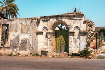 Fototapeta premium weathered ruins of a historical building with a green wooden door under the bright sun