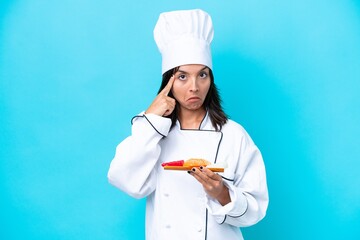 Young hispanic chef woman holding sashimi isolated on blue background thinking an idea