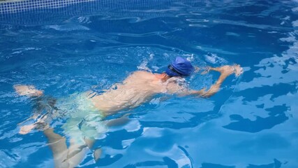 Man practices freestyle swimming in a clear pool, focusing on stroke technique and breathing for competitive training
