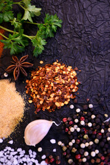 Seasoning for cooking. Pepper, salt, garlic, parsley on a black background. Ingredients to flavor food