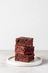Stack of chocolate brownies on white plate on white background isolated. Delicious dessert, text space