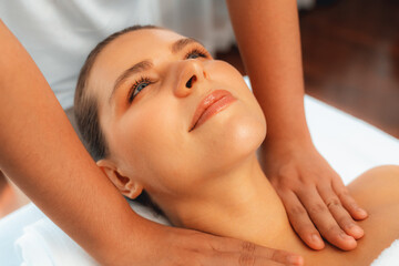 Naklejka premium Caucasian woman customer enjoying relaxing anti-stress spa massage and pampering with beauty skin recreation leisure in day light ambient salon spa at luxury resort or hotel. Quiescent