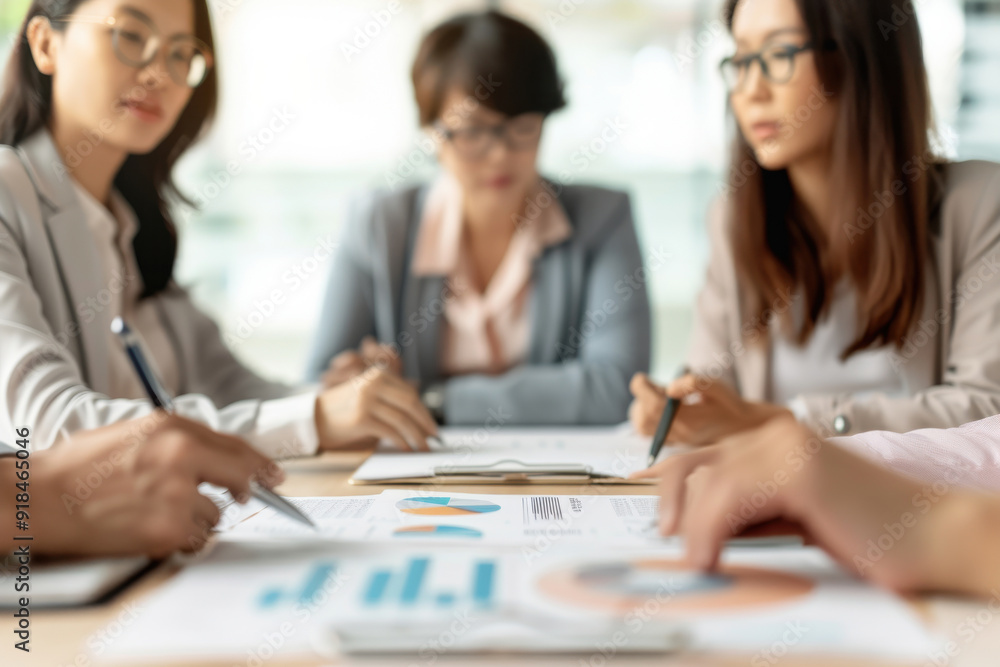 Poster a focused team meeting discussing analysis and strategies while reviewing financial graphs and chart