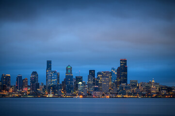 Naklejka premium Dramatic sunrise view of the beautiful Seattle, Washington skyline. Looking across Elliott Bay at the modern skyscrapers that line waterfront with city lights shining brightly.