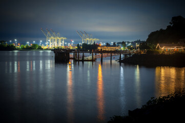 Public fishing pier with the Port of Seattle shipping cranes in the background. Sunrise view over...