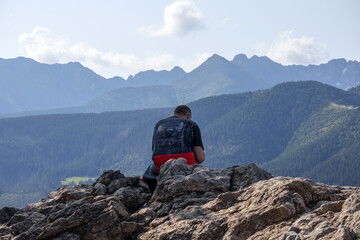 
the traveler sits on the top of the mountain and looks over the mountains