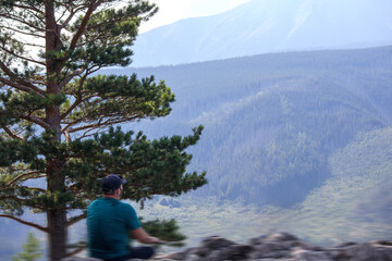 
a man sits on top of a hill and looks at the canes