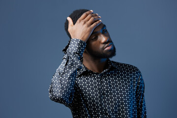 Stressed young african american man holding head in hands against blue background