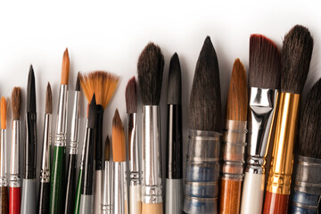 Fototapeta premium Mix of paint brushes in a row isolated on a white background.
