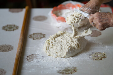 close up of an old woman hands cleaning the sticky dough with a knife