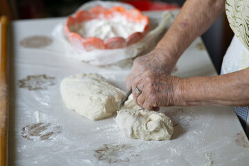 Close up of an old woman hands kneading bread dough on a table