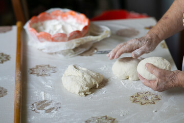 Close up of an old woman hands kneading bread dough on a table