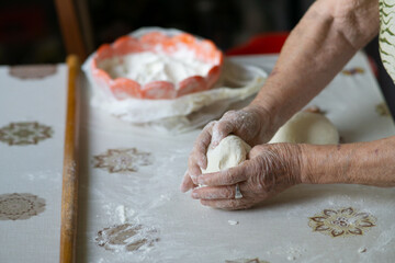 Close up of an old woman hands kneading bread dough on a table