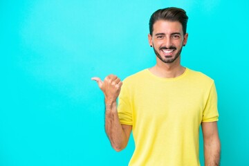 Young caucasian man isolated on blue background pointing to the side to present a product