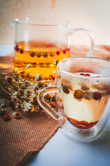 Cup of tea with pharmacy chamomile and lingonberry and sea buckthorn berries on a white table with...