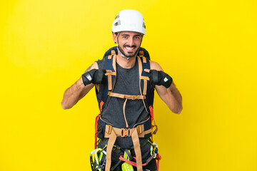 Fototapeta premium Young caucasian rock climber man isolated on yellow background with surprise facial expression