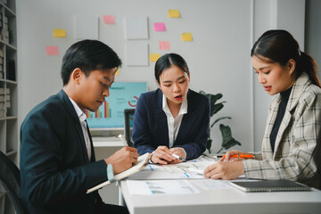 Team of young professionals is having a productive meeting, reviewing charts and discussing new business strategies