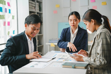 Team of asian entrepreneurs is working together, analyzing financial charts and using a calculator to calculate company profits
