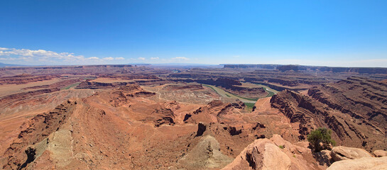 Panoramic view of Goose Neck, Colorado River and surrounding canyons from Dead Horse Point State Park near Moab, Utah under sunny summer cloudscape..