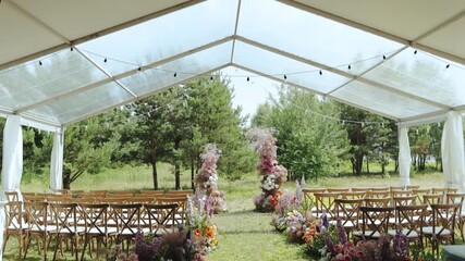 A beautifully elegant outdoor wedding ceremony setup arranged perfectly under a stylish tent