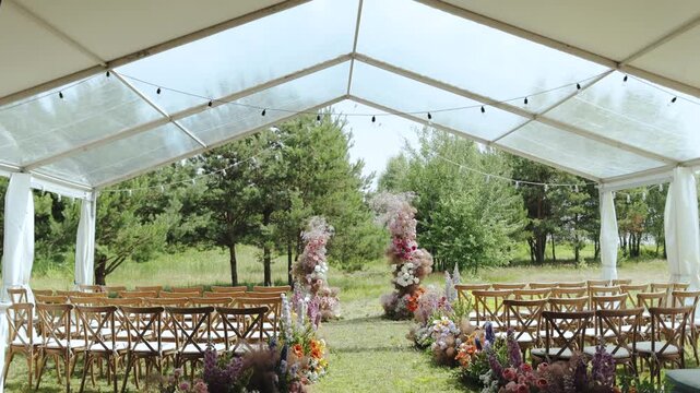 A beautifully elegant outdoor wedding ceremony setup arranged perfectly under a stylish tent