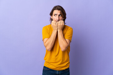 Young handsome man isolated on purple background nervous and scared putting hands to mouth